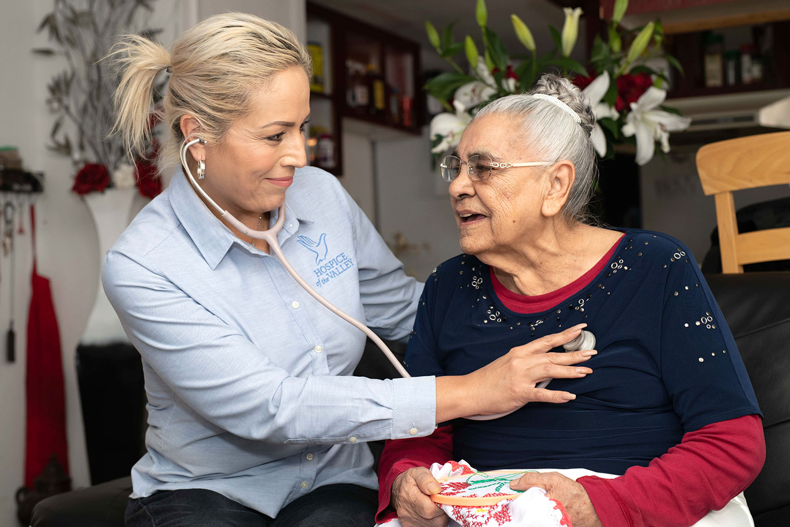 Skilled nurse takes heart rate of happy patient in a home visit
